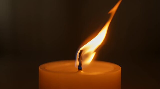 Warm inviting image of a candle flame flickering against a dark background
