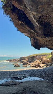 Sea cave framing the Pancake Rocks coastline at Truman Track, Punakaiki, West Coast of New Zealand. Layered limestone formations along the Tasman Sea.