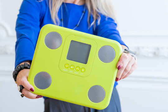 Young fit woman wear blue sweater holds scales isolated on white background, studio home gym. Workout sport concept. counting calories.fitness concept. Dieting and slimming theme.