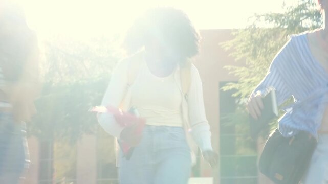 Diverse group of happy young college students running towards the camera on campus