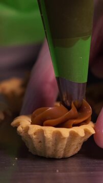 The pastry chef spreads jam on cookies. Vertical video.