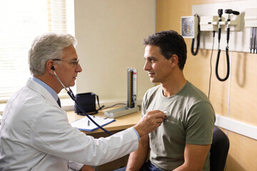 A doctor uses a stethoscope to examine a patient in a medical office.