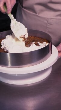 The process of making sponge cake. The concept of making confectionery desserts. The pastry chef applies the cream to the cakes.