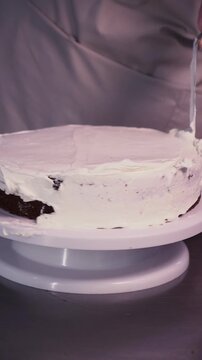The process of making sponge cake. The concept of making confectionery desserts. The pastry chef applies the cream to the cakes.