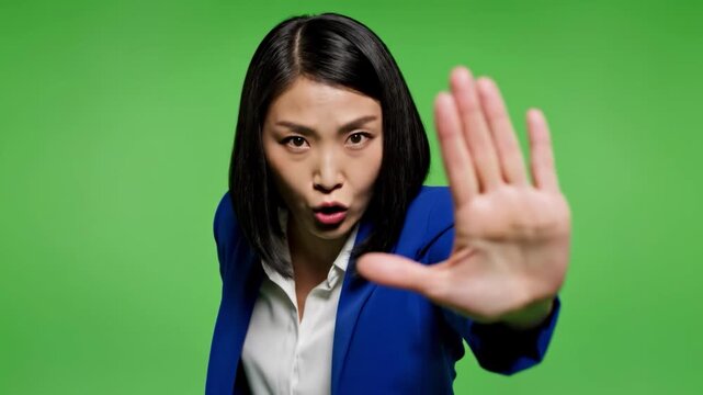 A businesswoman conveys a firm message of refusal with a raised hand. Ideal for concepts of boundaries, limits, or assertive communication in marketin
