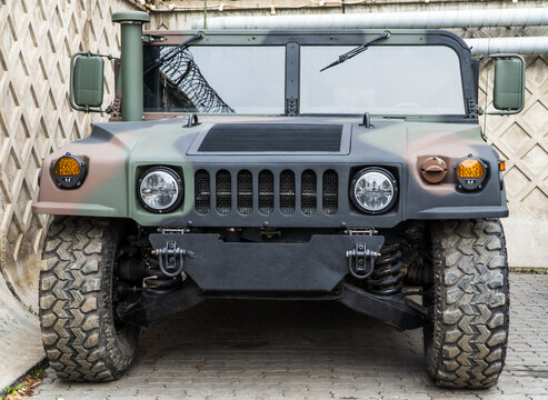 Military AM General HMMWV (Humvee) parked on an street, showcasing its rugged design and operational readiness in a secure military base. Khaki camouflage military Hummer front view. HMMWV.