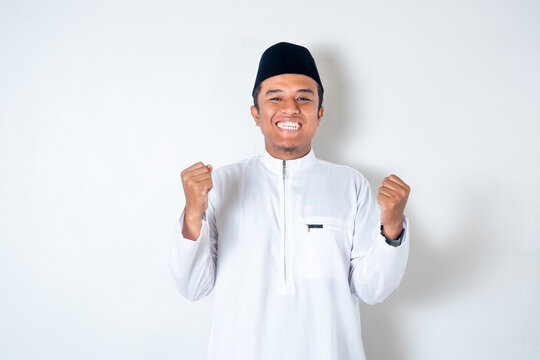 Successful happy muslim man screaming shouting and shows winning victory gesture over whiite background
