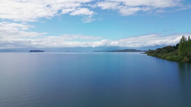 Forward flight over calm lake with islands and forested shore. Lago Ranco, Chile