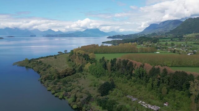 Forward flight over forested peninsula with lake and mountain range backdrop. Lago Ranco, Chile