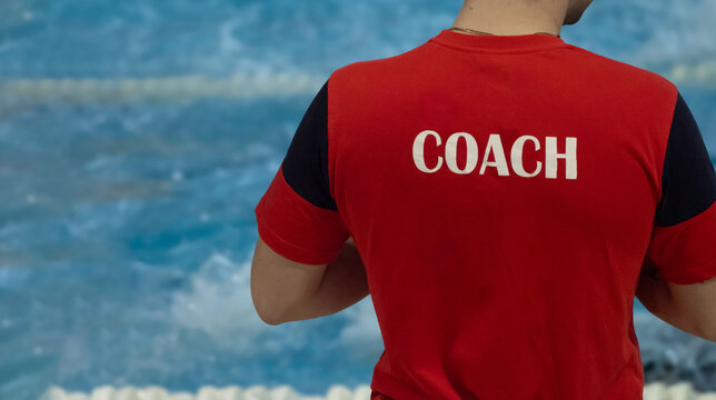Allenatore a bordo piscina con maglia rossa, concetto di coaching sportivo e leadership