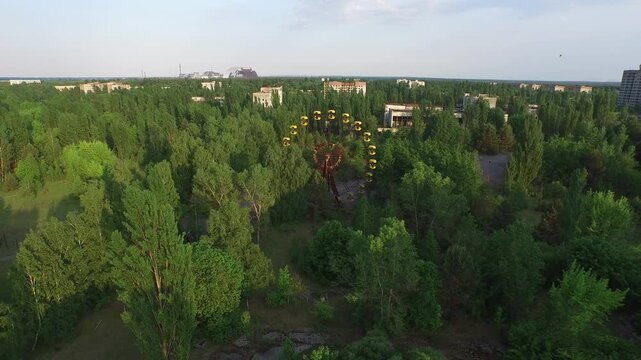 Drone footage reveals Pripyat's iconic, rust-laden Ferris wheel, now enveloped by the encroaching wilderness of the abandoned city.