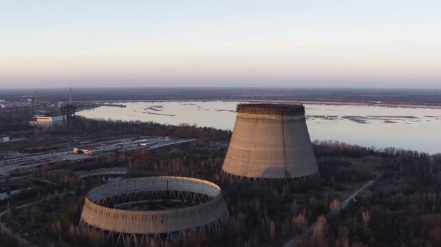 Aerial view of abandoned cooling towers for Chernobyl Reactor Blocks 5 and 6. Pripyat River and desolate trees surround the historic site, a stark reminder of the 1986 disaster.