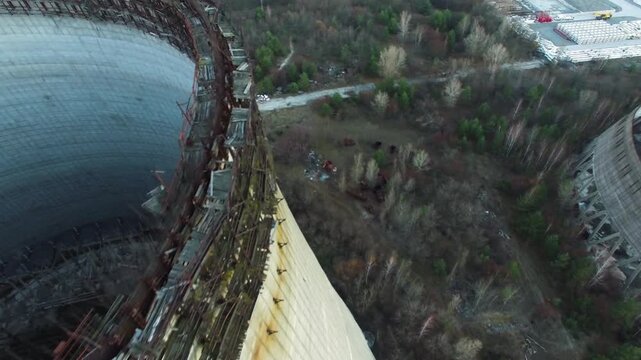 Aerial view of Chernobyl's unfinished reactor blocks 5 and 6. Decaying cooling towers, rusted scaffolding, and rewilded forest.