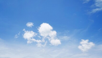 Fototapeta premium Beautiful white clouds floating in a clear blue sky. Natural daylight sky background with soft clouds. Blue sky texture with a calm and clean pattern.