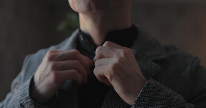 A businessman straightens his jacket and looks at the time on wristwatch