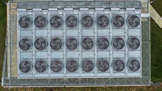 Top down aerial drone shot of symmetrical rows of industrial hvac cooling fans on a large warehouse roof for energy efficiency