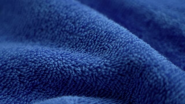 Blue terry towel fabric texture closeup. Soft cotton textile surface with fibers and folds. Rotation