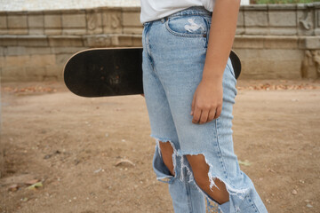 Person holding skateboard with ripped jeans outdoors © Jorge