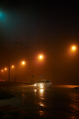 Naklejka premium White car. Night street in the fog in the light of streetlights in the city, photo at night