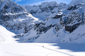 Obraz premium Czarny Staw Gasienicowy lake in Gasienicowa Dolina valley in winter in Tatra Mountains. Mountain winter landscape with frozen lake. High Tatras, Poland