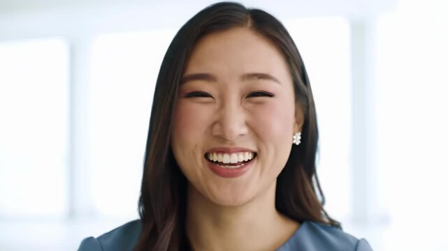 A relatable young adult, in simple modern attire, makes direct eye contact, smiling and laughing in a bright white studio with soft bokeh. Uplifting commercial concept