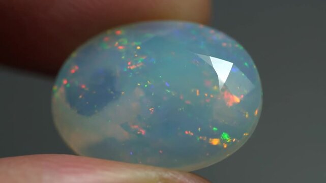 Hand holding beautiful faceted opal gemstone with fiery play of color