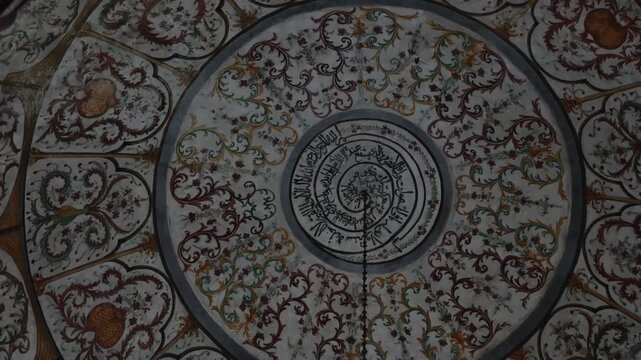 A look up at the windowless semi-spherical dome and ornate ceiling featuring eighteenth century landscape frescoes and intricate floral patterns within the historic Ottoman prayer hall