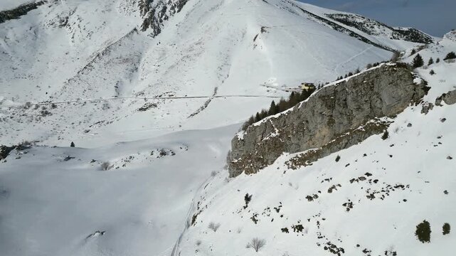Aerial drone footage of Monte Altissimo, Italy: snowy alpine landscape with rocky ridges and frozen trees under clear winter light. Ideal for nature, mountain and scenic projects.