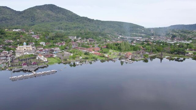 Sacred Balinese Temple And Muslim Mosque On The Shore Of Lake Beratan In Bedugul, Bali With Mountain Backdrop And Village Landscape &mdash; Daytime Aerial Drone View