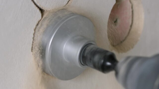 Close-up drilling of wall with circular bit for mounting electrical outlet boxes in apartment renovation. High quality 4k footage