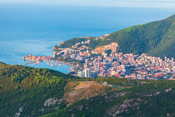 Obraz premium Aerial shot captures coastal town of Budva, Montenegro, nestled between lush green mountains and Adriatic Sea. Budva historic Old Town and modern developments line the scenic Riviera