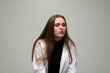 Fototapeta premium Young woman with long hair looking away, expressing doubt and uncertainty against a plain background