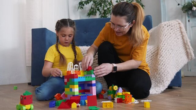 Building colorful block tower together mother and daughter play with toy block on living room floor parent guiding child in creative family activity indoor cooperation learning and concentration