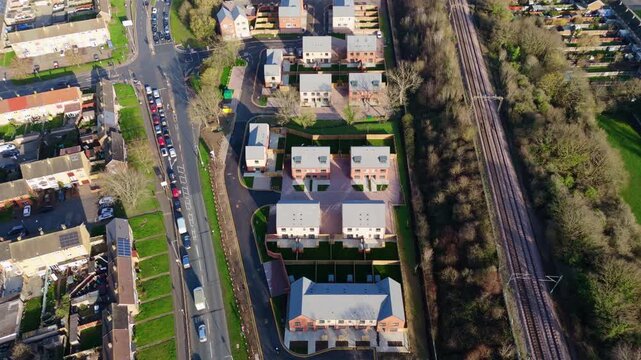 Reverse aerial view of new houses in Basildon, England, next to a road and railroad tracks