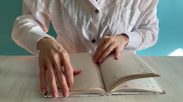 closeup of hands turning pages in an open planner notebook on a tabletop,organized lifestyle and productivity concept with clear paper rustling,study and planning routine video with sound