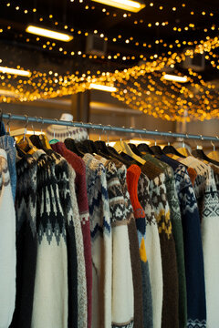 Vertical shot of Icelandic wool sweaters under warm festive lights in a market.