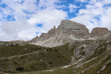 Fototapeta premium Dolomite peaks rising above alpine terrain with clouds passing gently across the ridges