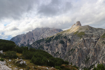 Fototapeta premium Dolomite peaks rising above alpine terrain with clouds gently passing overhead
