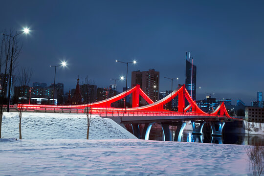 New red bridge across the Moskva River connecting the Mnyovnikovskaya and Filevskaya floodplains illuminated in the night, Moscow, Russia
