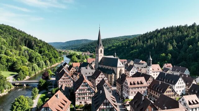 Traditional German town by river with church and green hills
