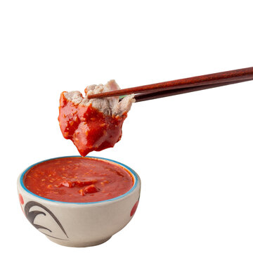 chopsticks picked pork dipped into a bowl of sukiyaki sauce, Many vegetables in white bowl include carrots, baby corn, shiitake mushrooms, golden needles, celery and chicken eggs.