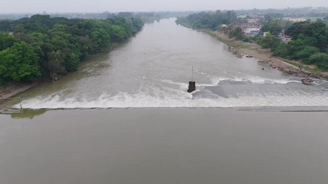 Aerial view of Kharun river dam and flowing water, Drone shot of river barrage with city landscape, Scenic river overflow at dam with bridge view, Top view of water flow on Kharun river weir.