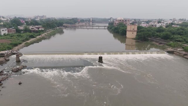 Aerial view of Kharun river dam and flowing water, Drone shot of river barrage with city landscape, Scenic river overflow at dam with bridge view, Top view of water flow on Kharun river weir.