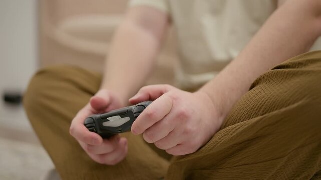 Young man's hands playing video game with console controller