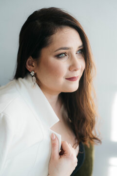 Beautiful green-eyed brunette posing smiling. The woman is dressed in an office style. Portrait of a Happy Woman. A beautiful woman in white looks thoughtfully into the distance. 