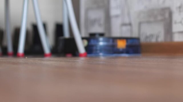 Modern robot vacuum cleaner performing wet cleaning on a laminate floor under furniture. Autonomous smart home technology for effortless domestic housework and hygiene