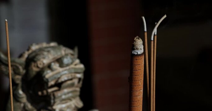 Close-ups and shallow depth-of-field shots capture the moment when incense is burning, and smoke swirls in the temple, showcasing a solemn and tranquil cultural image.