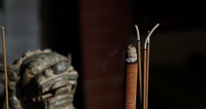 Close-ups and shallow depth-of-field shots capture the moment when incense is burning, and smoke swirls in the temple, showcasing a solemn and tranquil cultural image.