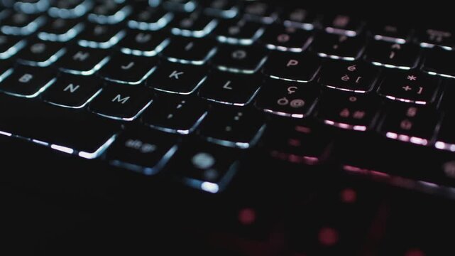 Dark laptop keyboard with red backlight accents in shallow depth of field.