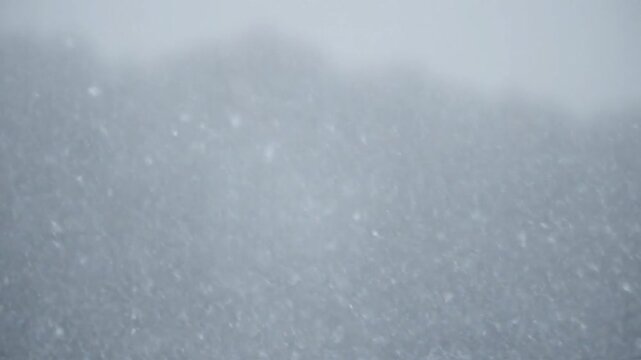 Snowflakes gently falling on a serene mountain landscape
